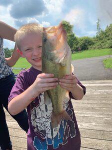 Boy proudly holds a fish he just caught.